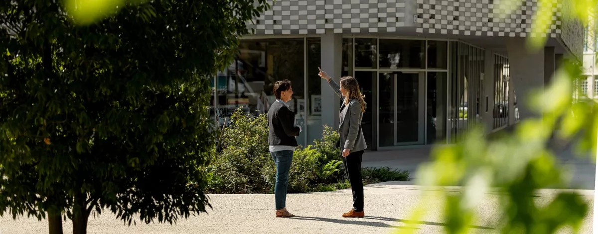photo de Léna avec une cliente devant un bâtiment entouré de verdure.