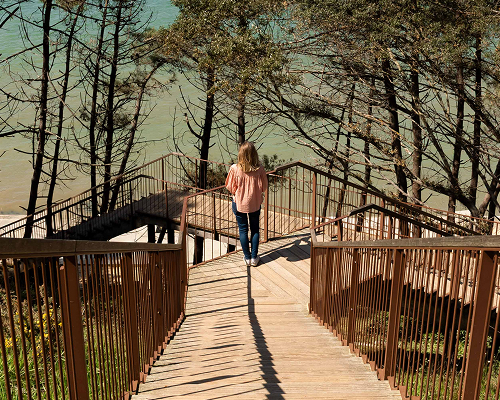 Photo de Léna de dos face à la mer pensive au pied d'un escalier.